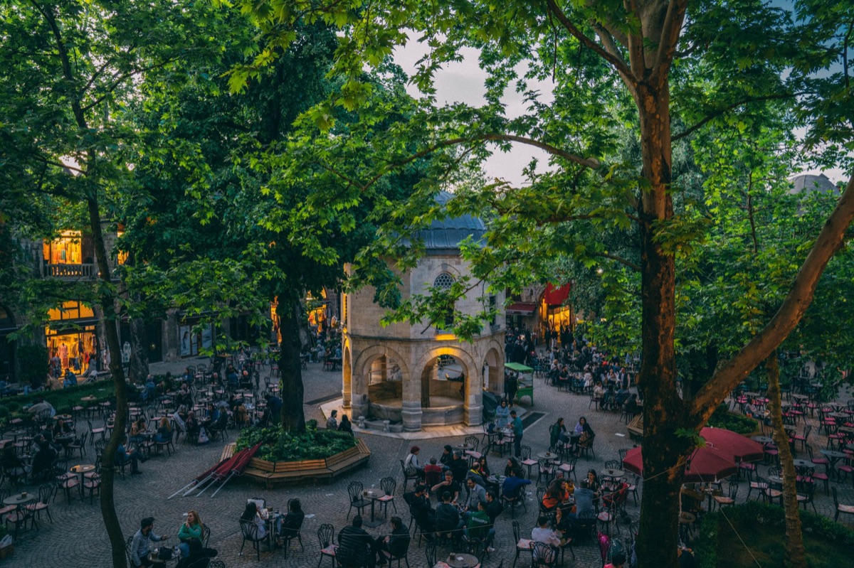 Une foule se rassemble dans une place publique en discutant d'un restaurant controversé